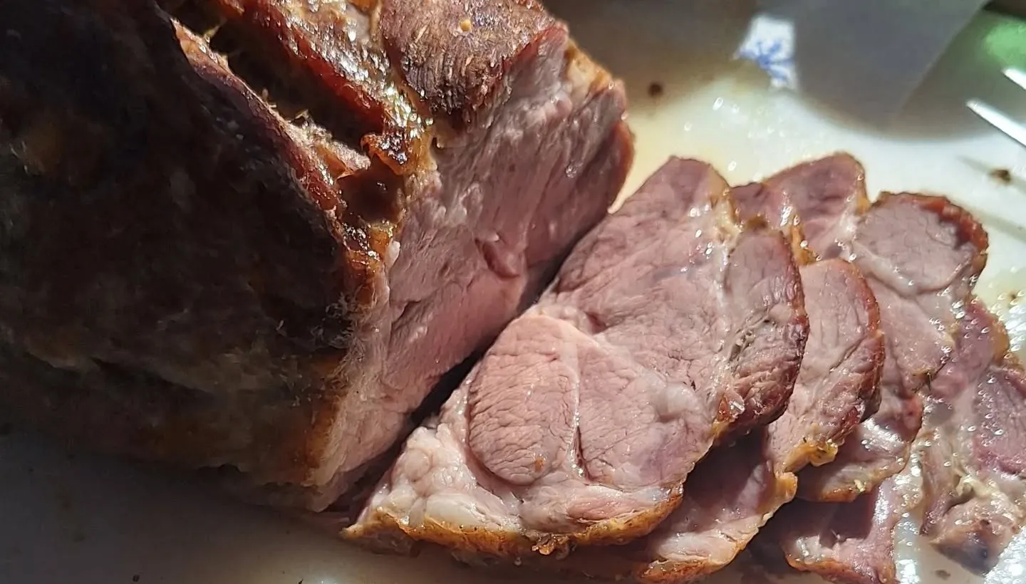 Frisch aufgeschnittener Schweinsbraten mit knuspriger Kruste, in Scheiben auf einem Schneidbrett
