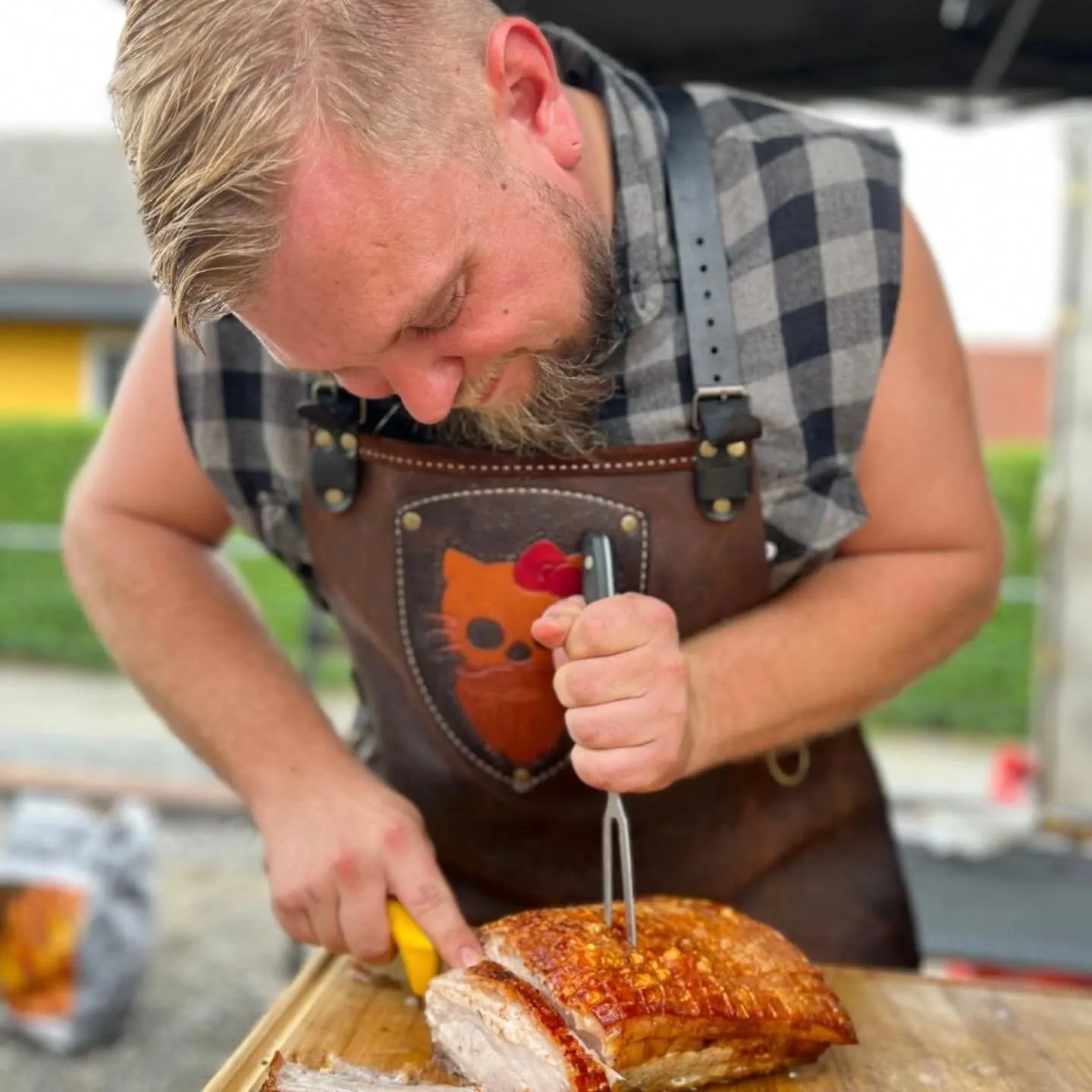 Raphael Fössl tranchiert einen frisch gegrillten Schweinsbraten mit knuspriger Kruste